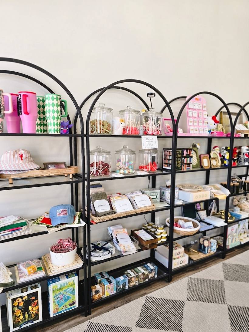 Arched black display shelves with insulated tumblers, candy jars, socks, and puzzles